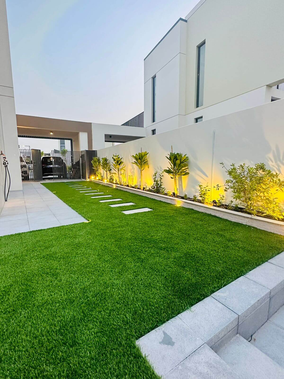 Newly landscaped villa garden in Dubai with fresh lawn, palm trees and stone paving